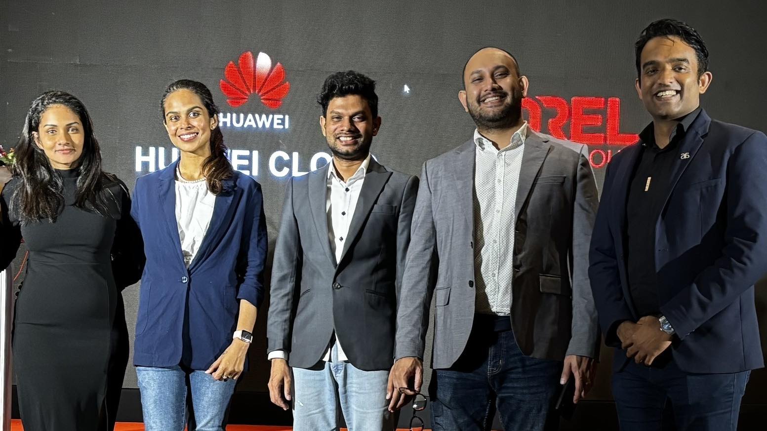 Lesith Dissanayaka (2nd from the right) in a white shirt and a grey jacket at an event with Arimac CEO Chamira Prasad Jayasinghe to his left, and fellow colleague to his right.